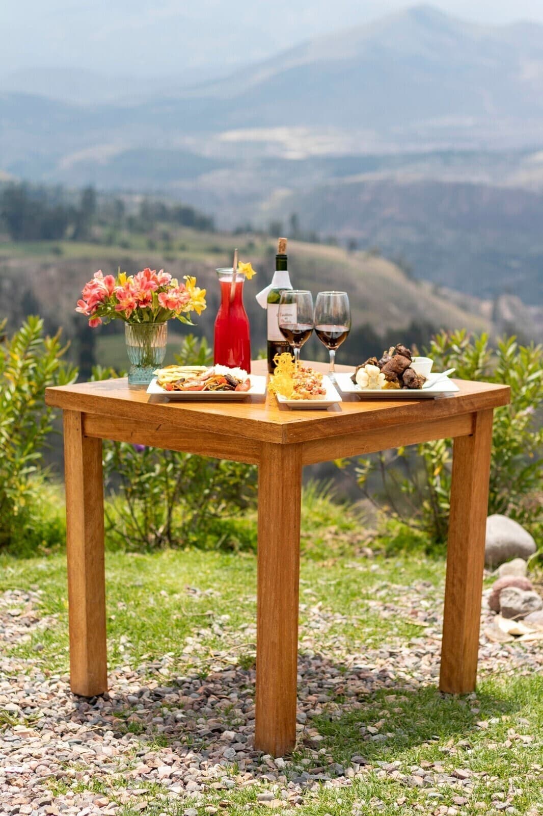 Una mesa de QuinuaQ con platos, flores y bebidas frente al valle